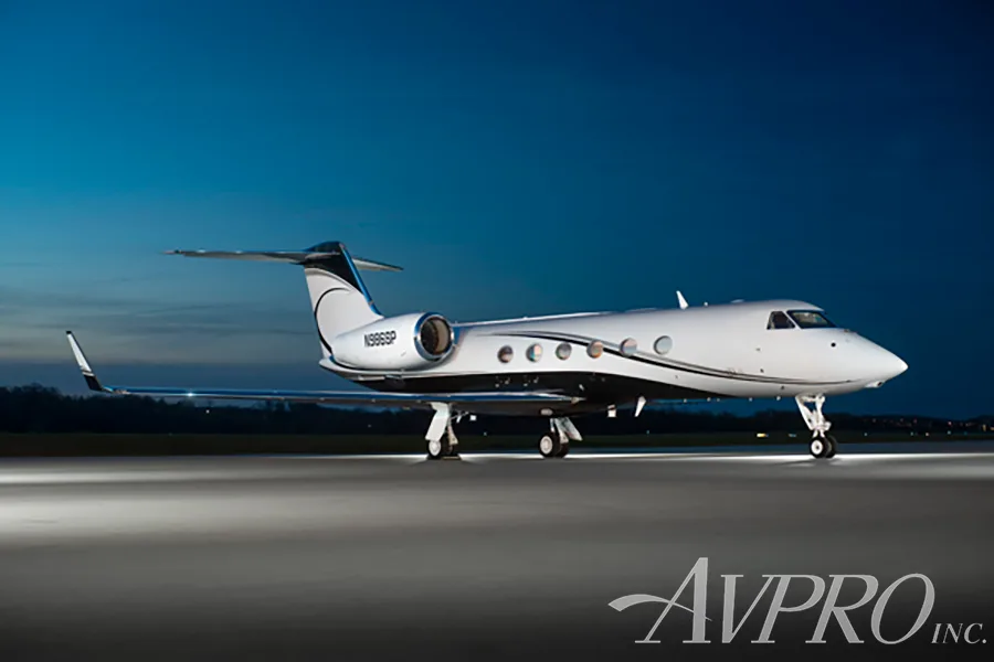 A white and black Gulfstream G550 (N986SP) parked on a tarmac at night under a dark blue sky.