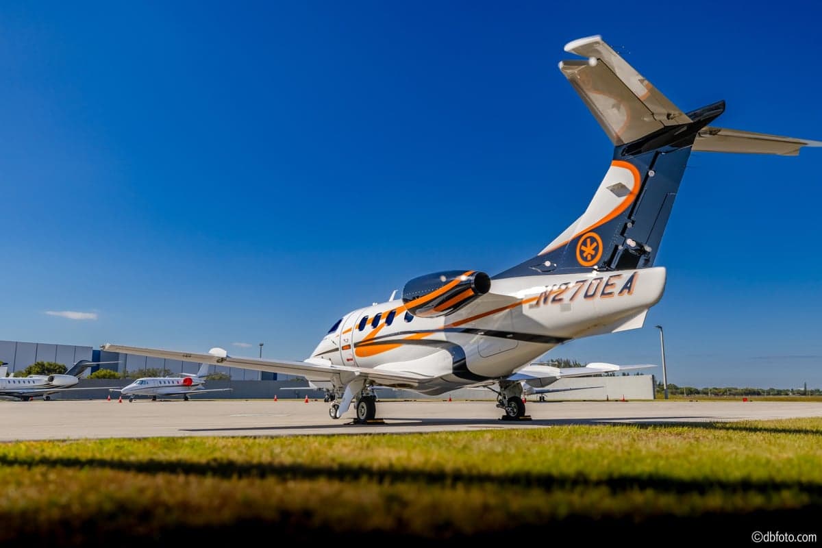 The tail of a Phenom 100 aircraft with registration N270EA parked on the tarmac.