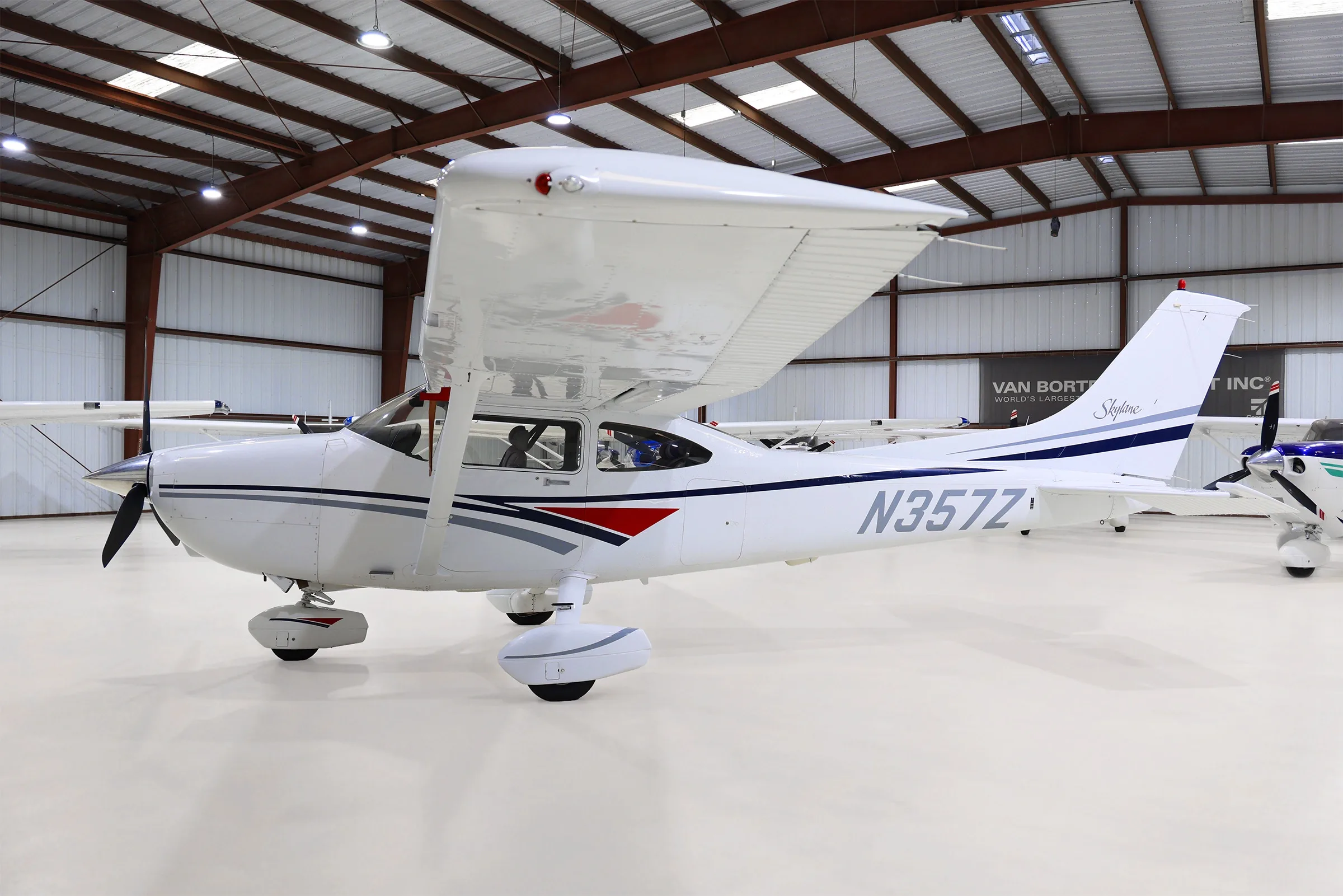 Side view of a white Cessna Skylane N357Z with grey and blue stripes, parked in a hangar.