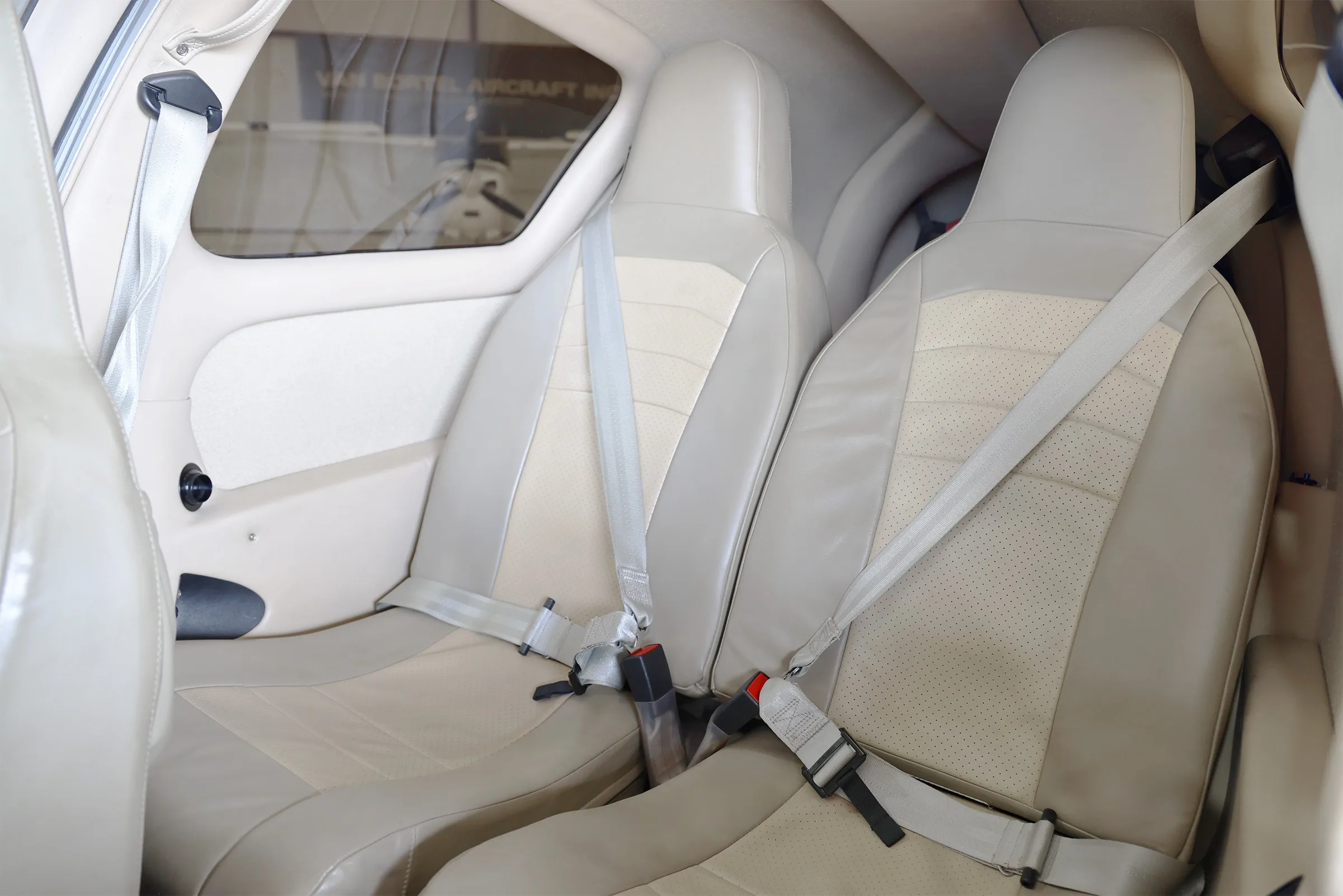 The light-colored leather passenger seats with seatbelts in the aircraft's cabin.