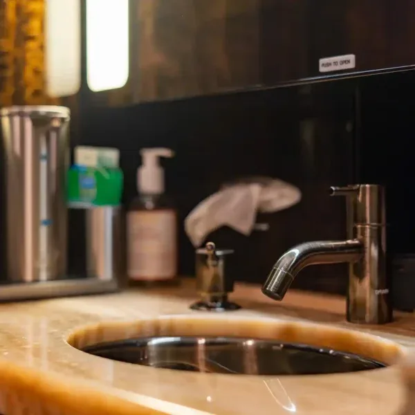 A close-up of a modern sink with a metallic faucet and toiletries in the aircraft lavatory or galley.