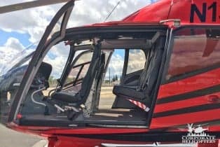 View of the interior of the helicopter with black seats and open door.