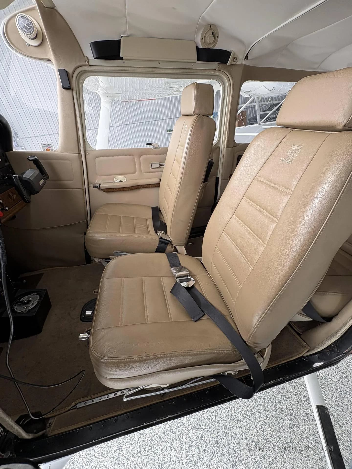 The tan leather front pilot and co-pilot seats in a small aircraft cabin.