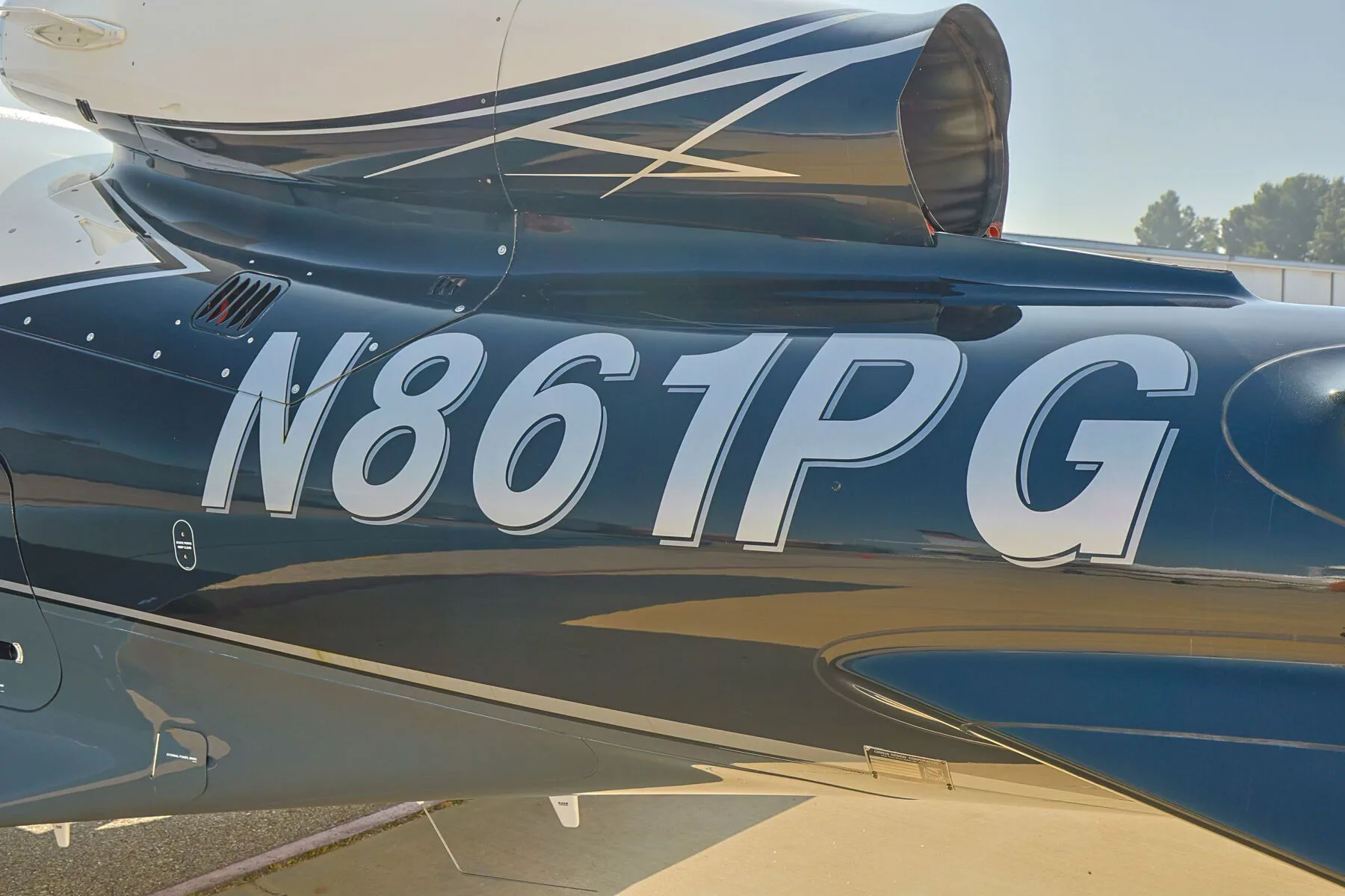 Close-up of the N-number "N861PG" on the fuselage of a Cirrus Vision Jet, with the engine intake visible.