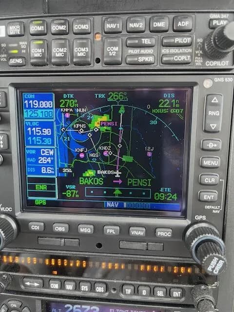 A close-up view of an aircraft's GPS navigation display showing a flight plan and surrounding controls.