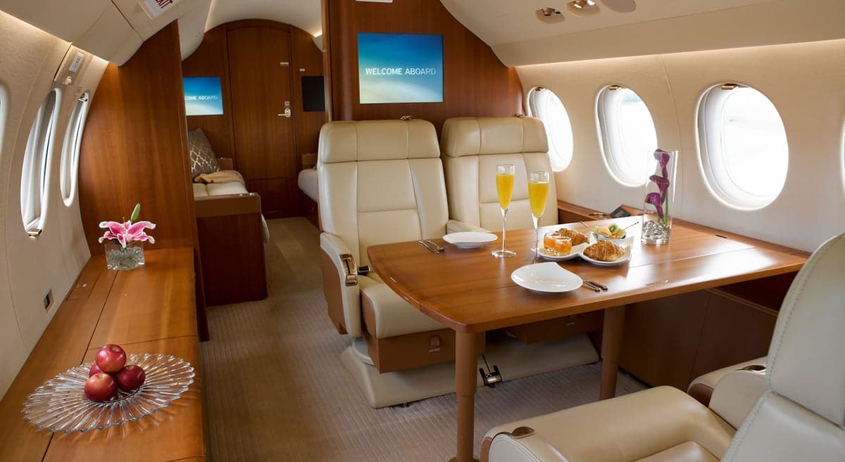 View of the aircraft's interior with seating, tables, and a welcome screen.