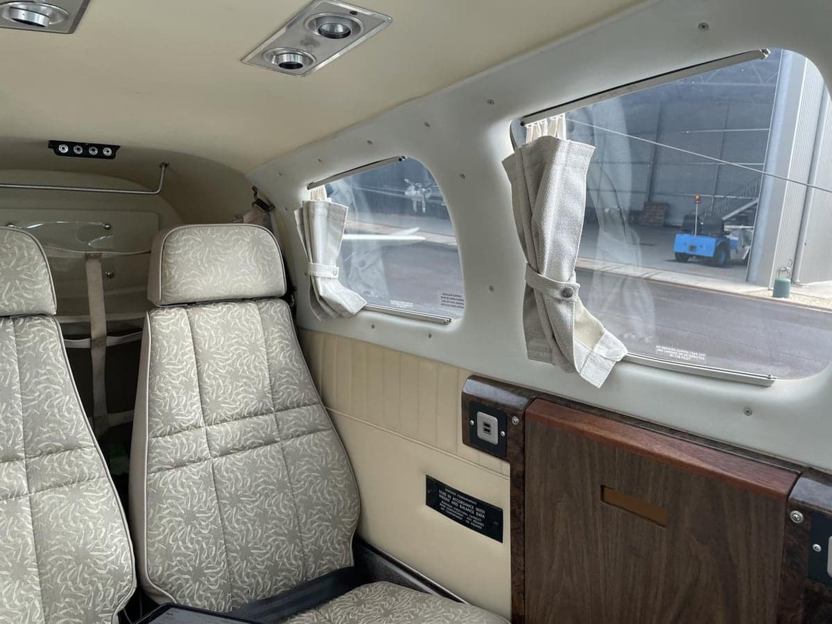 The aircraft's interior shows the rear seats and side paneling.
