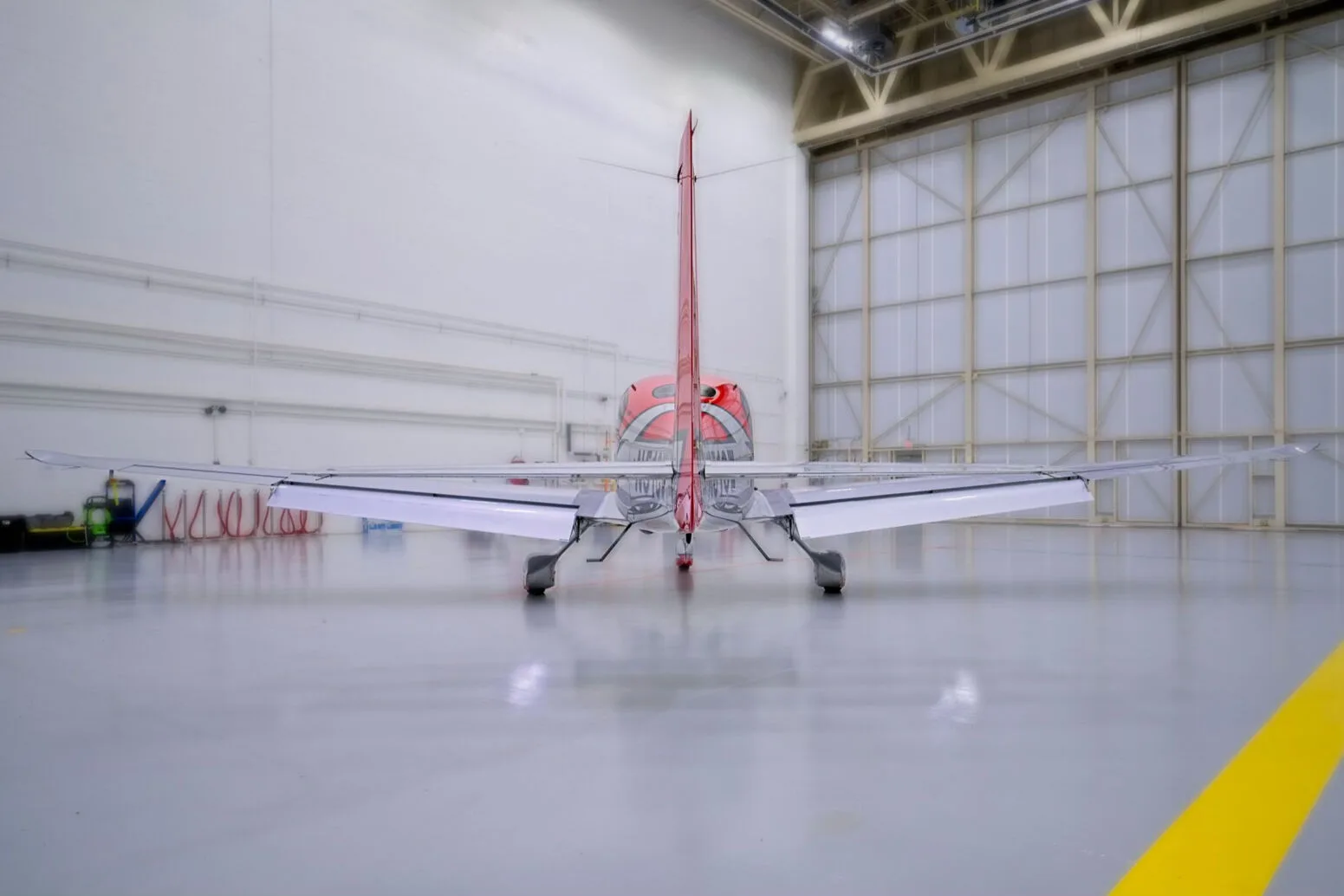 A rear view of a red and white Cirrus SR22 aircraft with registration N51CW in a hangar.