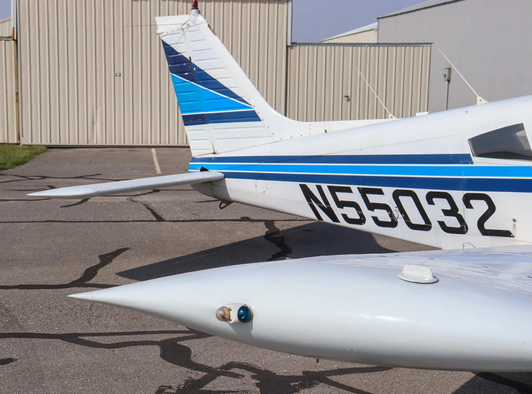 A close-up view of the tail section of the white Piper Cherokee 235, showing the blue stripe livery and registration N55032.