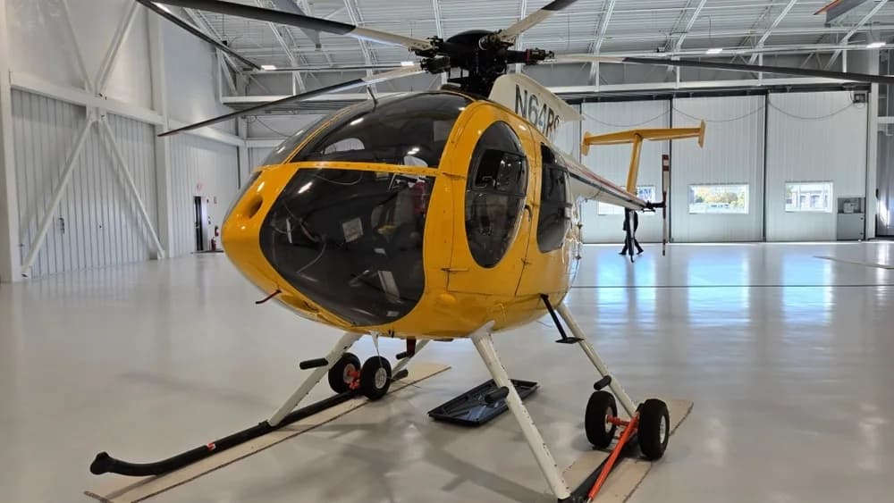 A front-left view of the yellow N64RS helicopter parked in a spacious hangar.