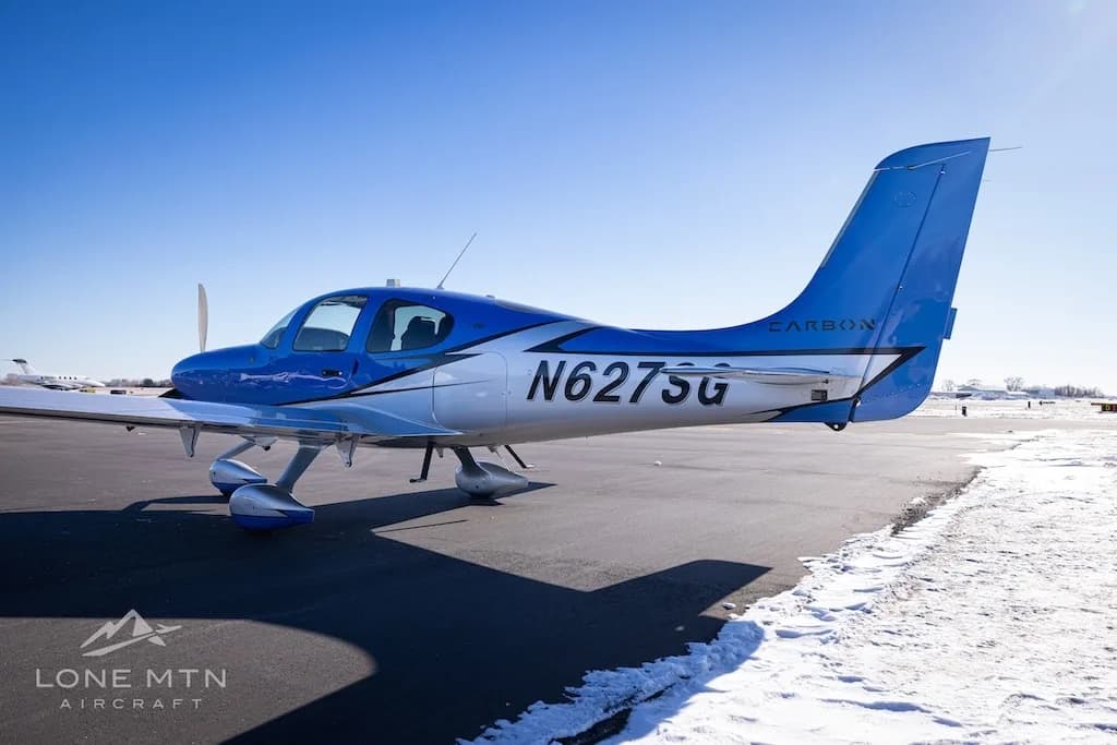 A close-up side view of the rear fuselage and tail of the blue and silver Cirrus SR22 (N627SG).