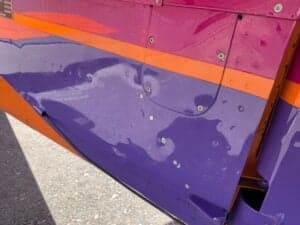 Close up of the wing of the orange and purple aircraft.