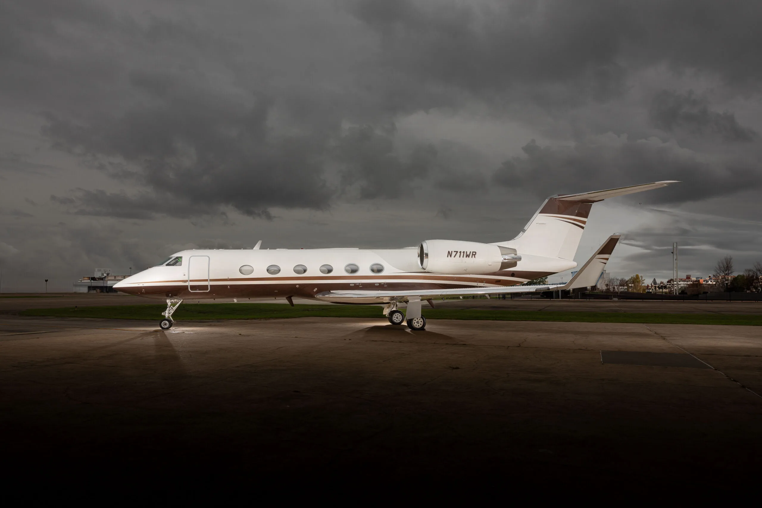 Gulfstream G-IV with registration N711WR on the tarmac under a cloudy sky.