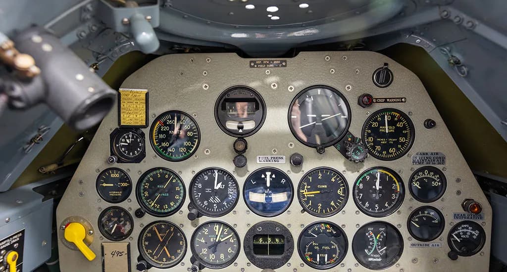 A detailed view of the full instrument panel of a vintage aircraft, filled with various gauges and controls.