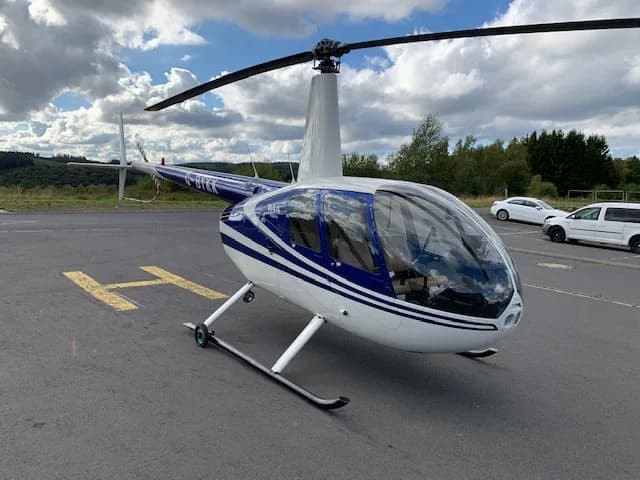 Robinson R44 Raven with blue and white paint scheme on a helipad.