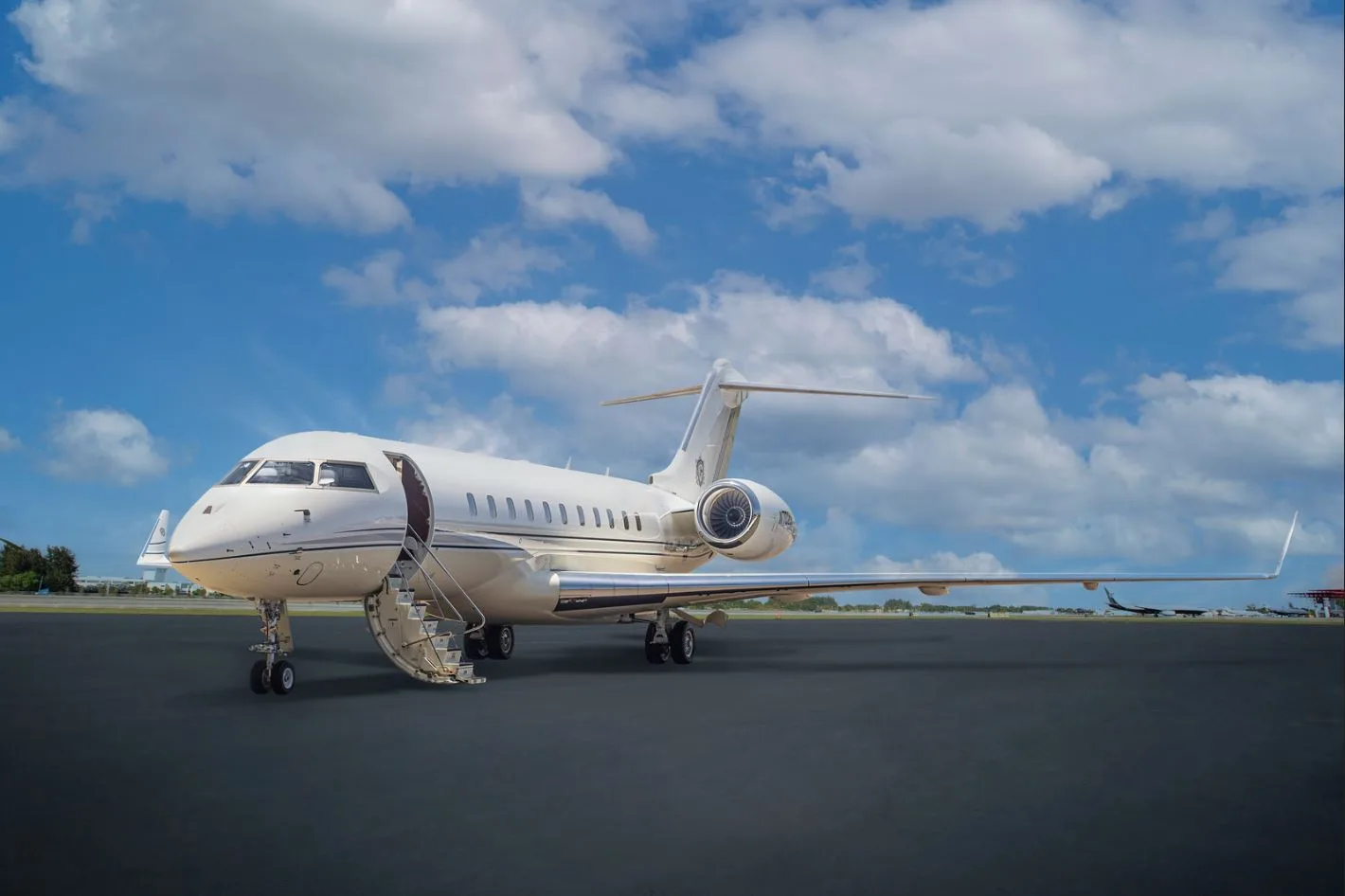 A white private jet parked on the tarmac with the stairs down.