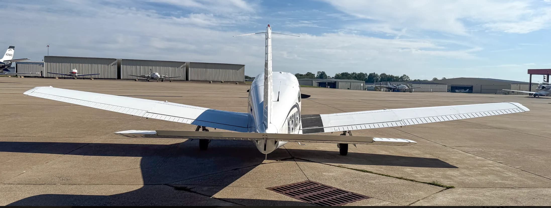 A rear view of the white Piper Arrow III aircraft, tail number N751KS, parked on an airport tarmac.