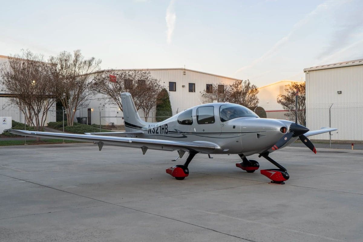 A Cirrus SR22T aircraft with a silver paint scheme parked on the tarmac.