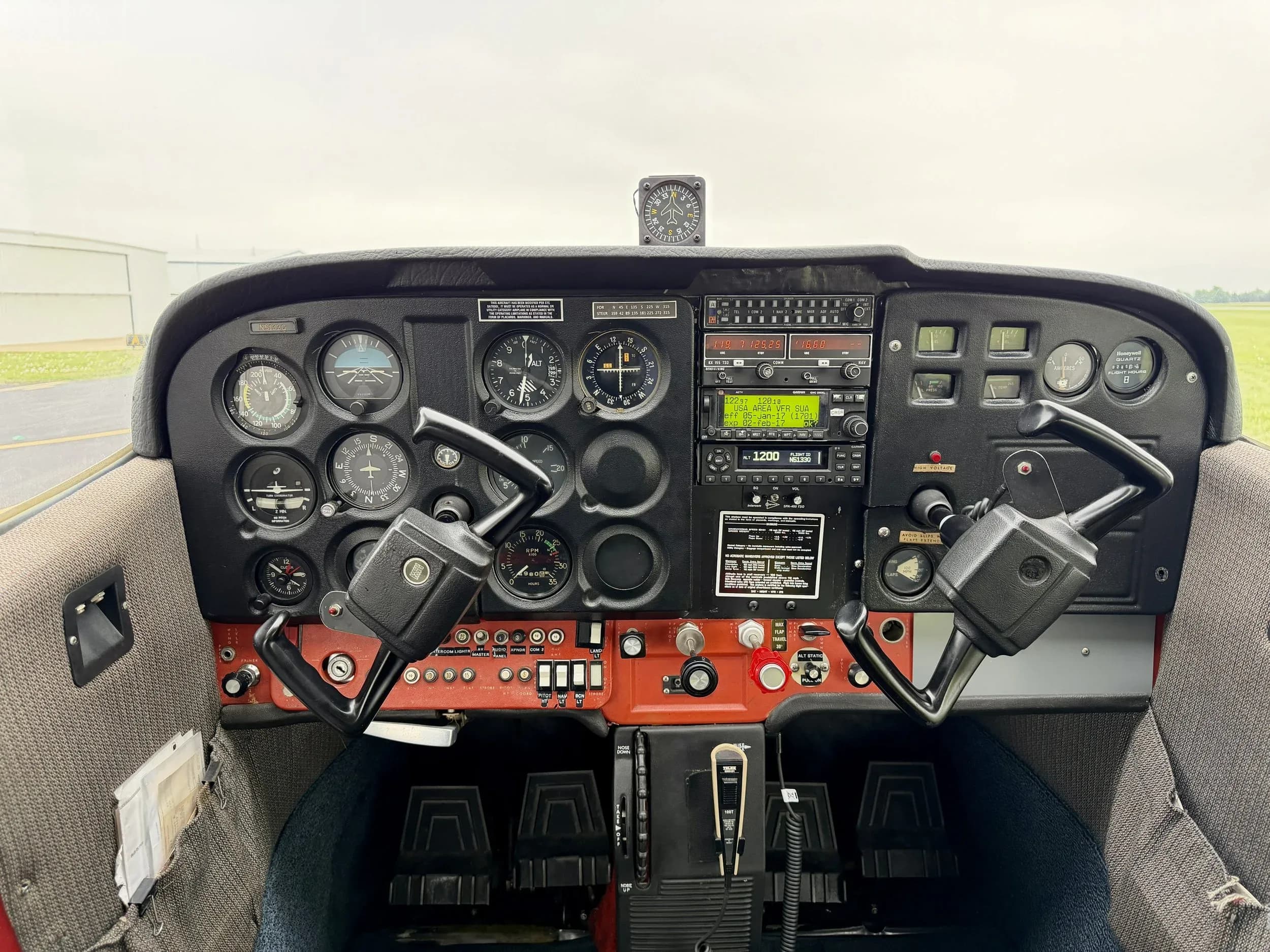 The cockpit of a small aircraft, showing the instrument panel with analog gauges and two control yokes.
