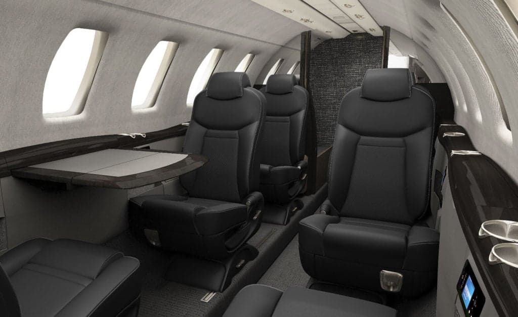 The interior of a Citation CJ4 aircraft with black leather seats.