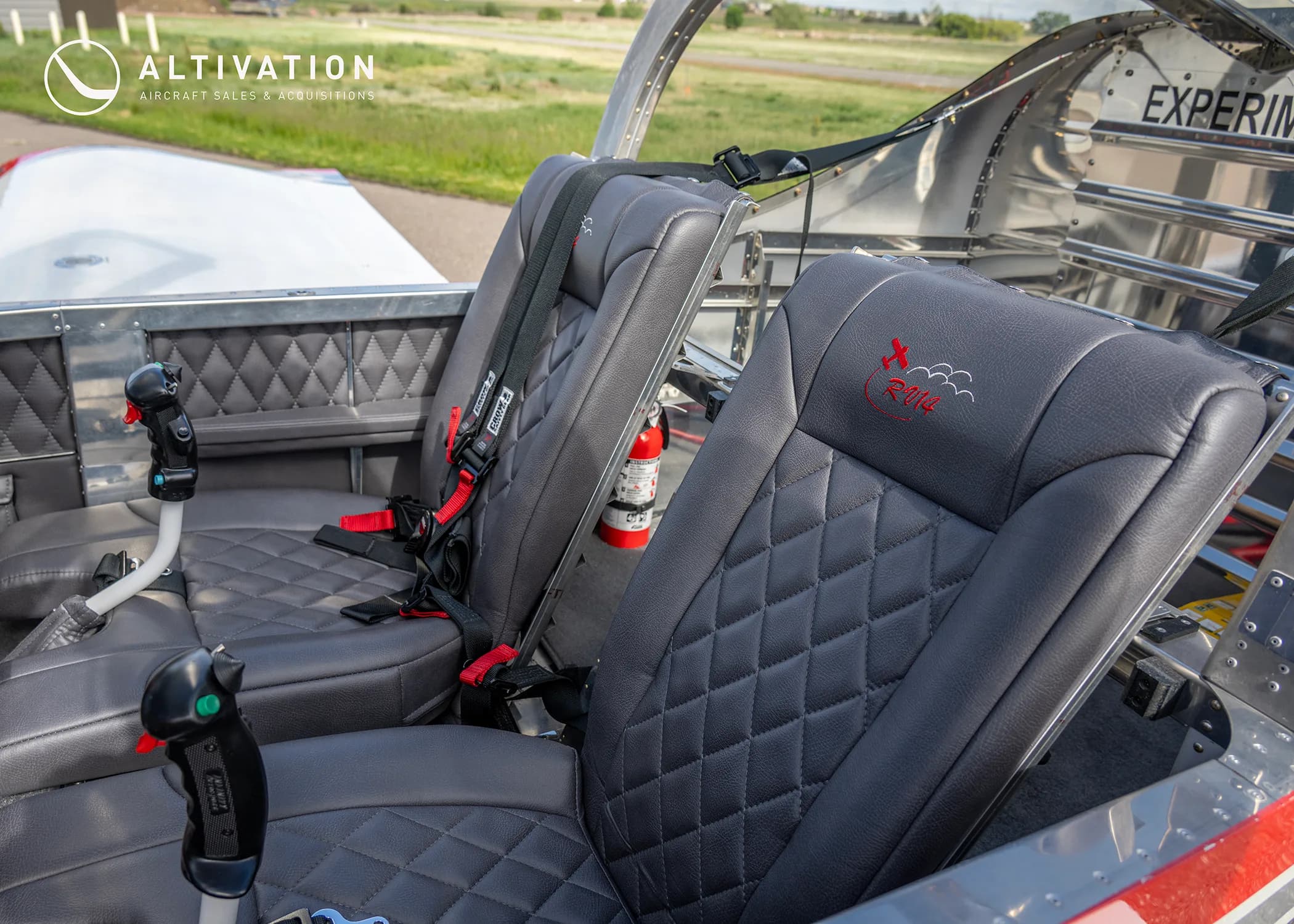 The two black quilted leather seats with red stitching in the interior of an experimental aircraft.