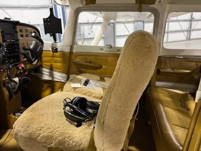 The interior of the aircraft features sheepskin-covered pilot seats and brown side panels.