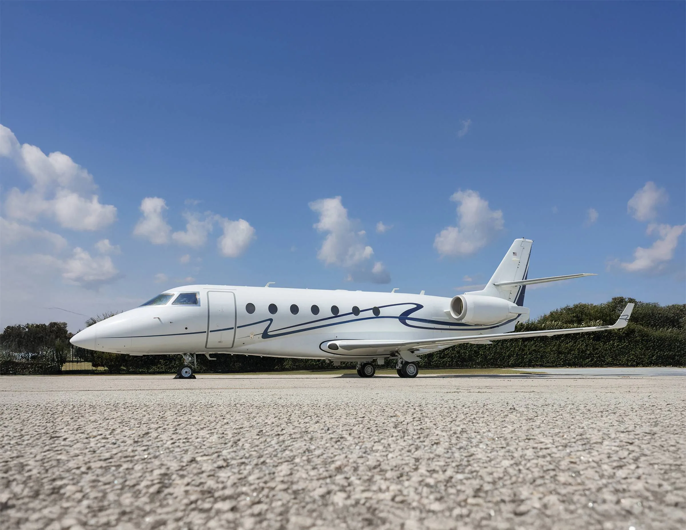 White aircraft with blue accents parked on the tarmac under a blue sky.