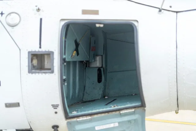 Close-up view of an open compartment on the side of a white helicopter.