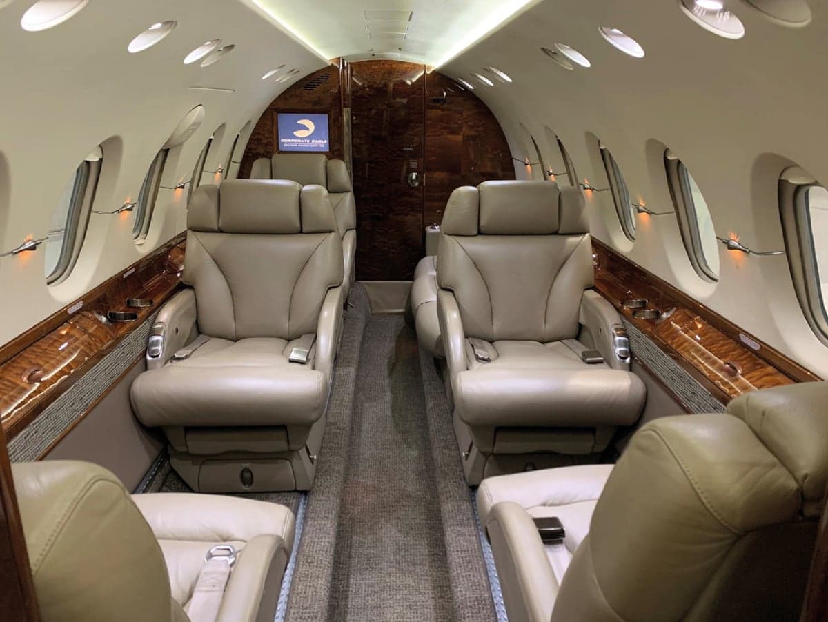 Aircraft cabin with leather seats and wood trim.