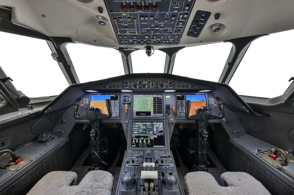 The cockpit of an aircraft with multiple screens and controls.