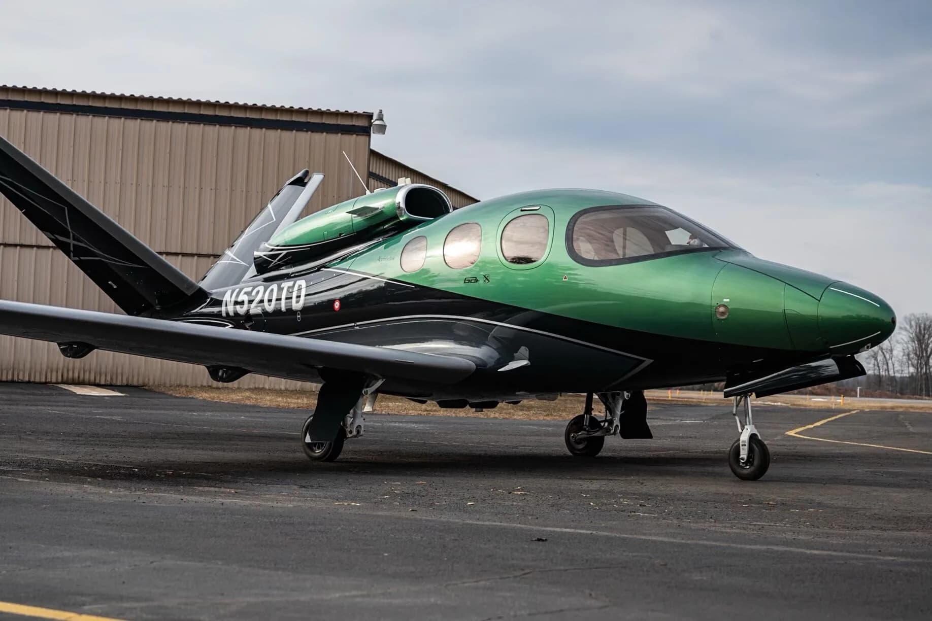 A side profile of the Cirrus Vision Jet N520TD in green and black paint scheme on an airfield.