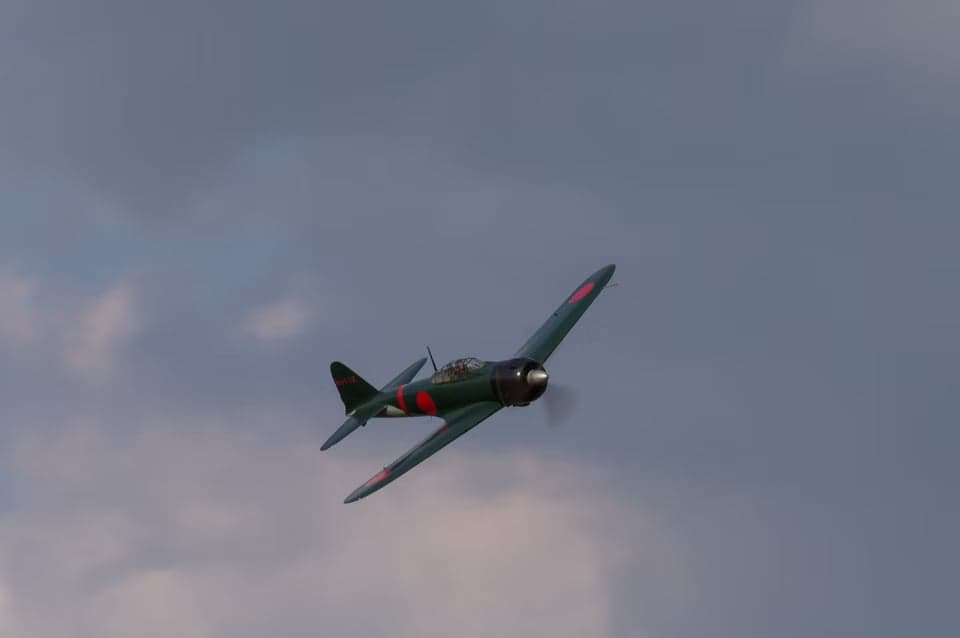 A Mitsubishi A6M Zero taking off from a grassy field.