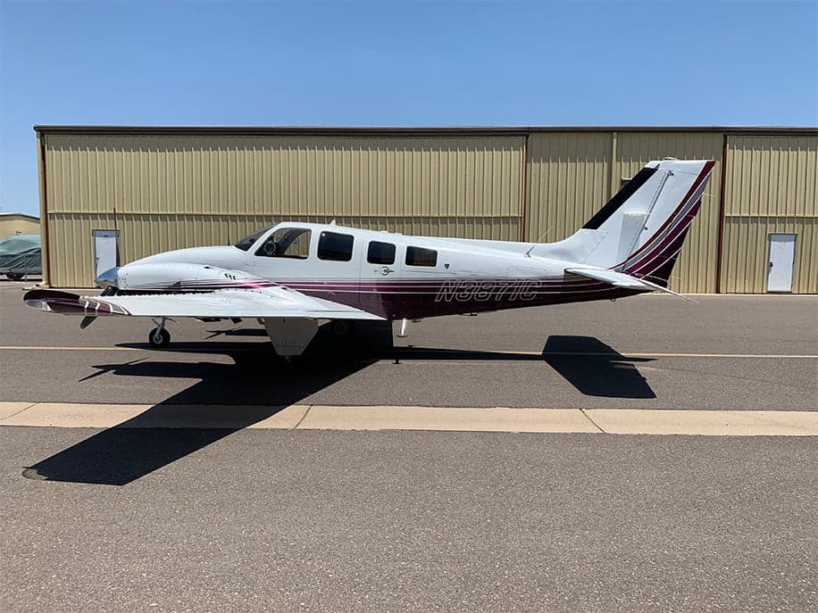 Side view of the N3871C aircraft on the tarmac with a white and burgundy paint scheme.