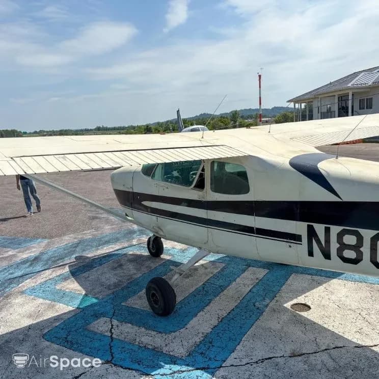Close-up side view of the cockpit area of a white and black Cessna 172 N8032T on an airfield.