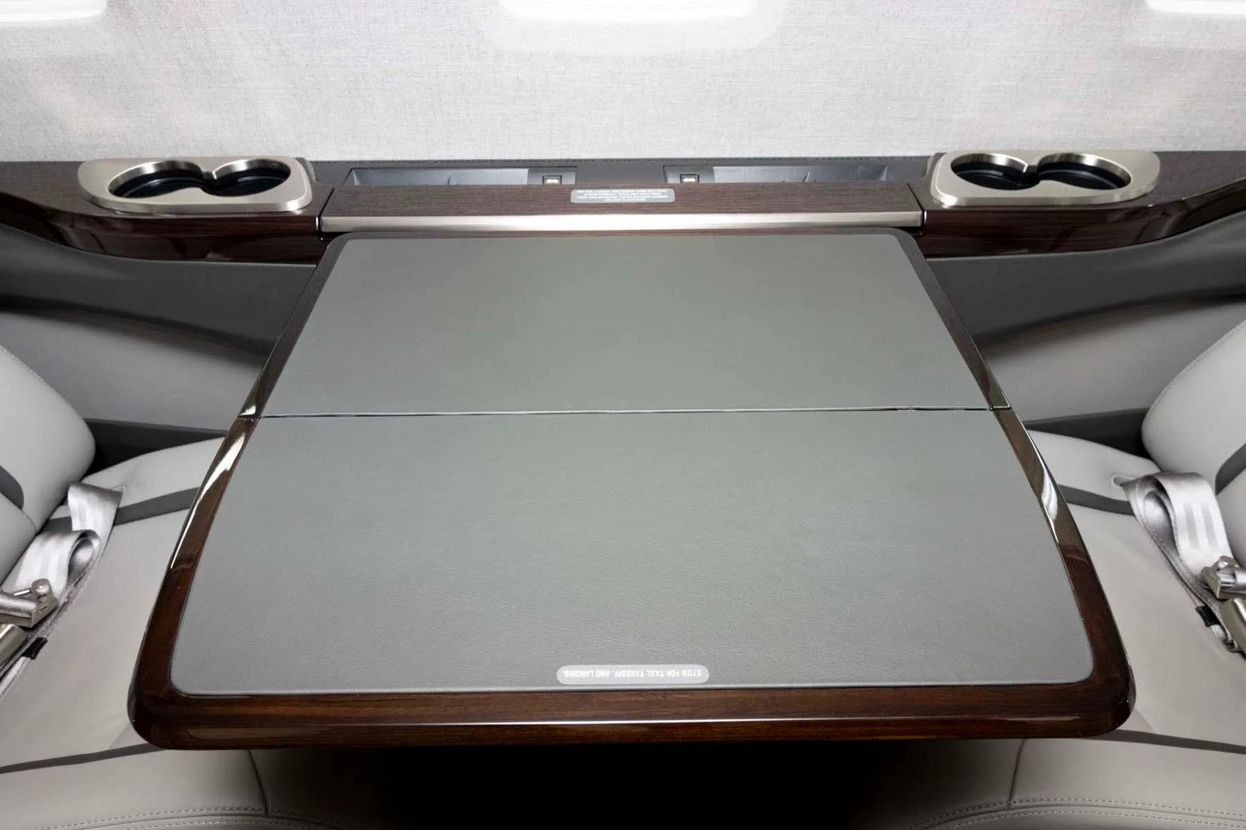 A grey leather table extended from the side panel in the private jet's cabin.
