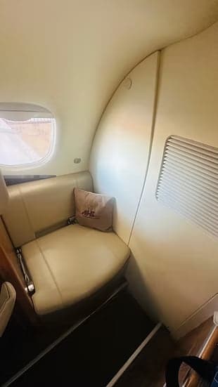 Close-up of a single leather seat with a pillow inside the aircraft.