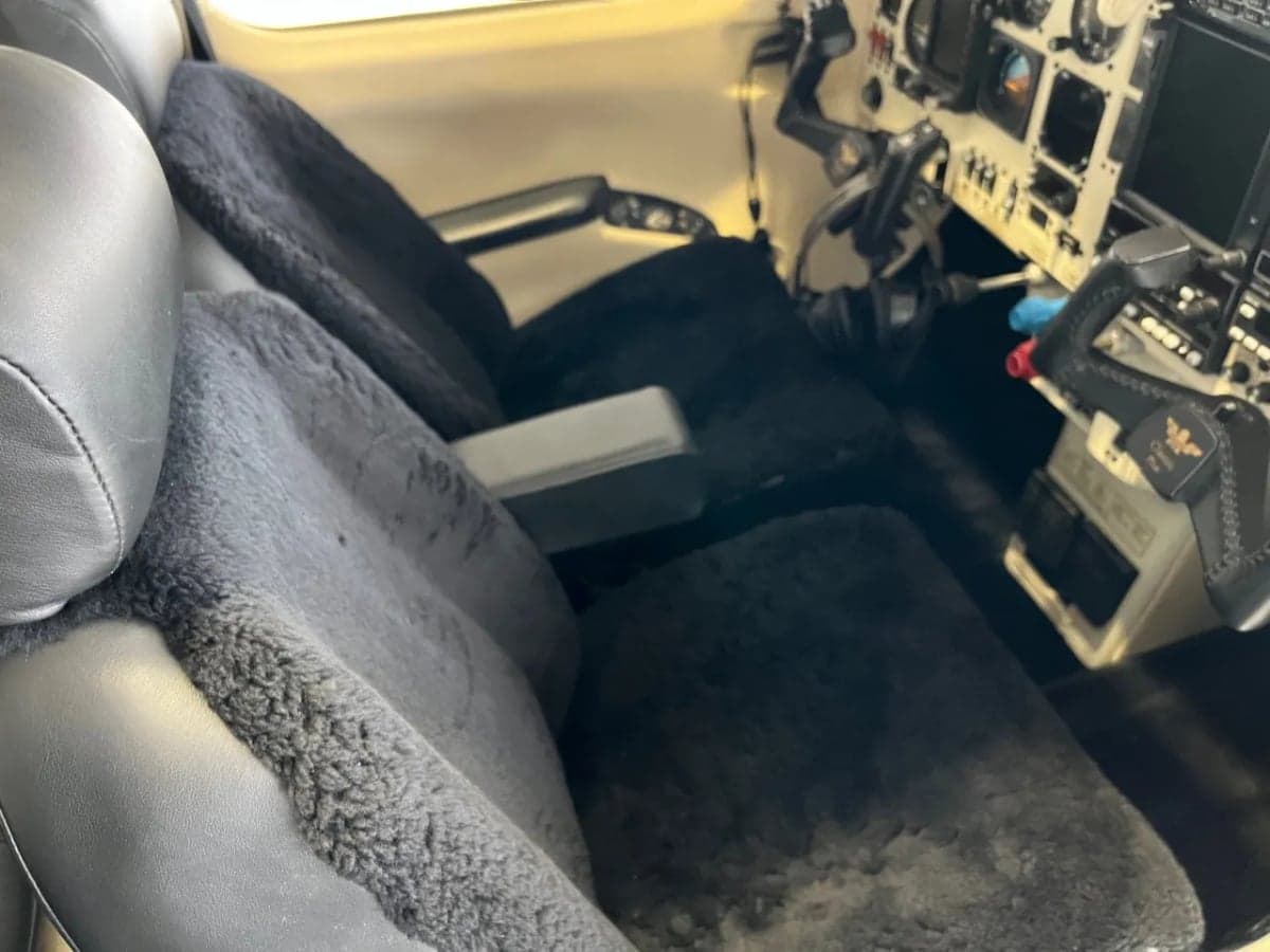 View of the aircraft's front seats with sheepskin covers and the instrument panel.