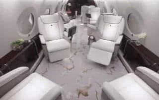 A view of the aircraft's interior with white leather seats and marble flooring.