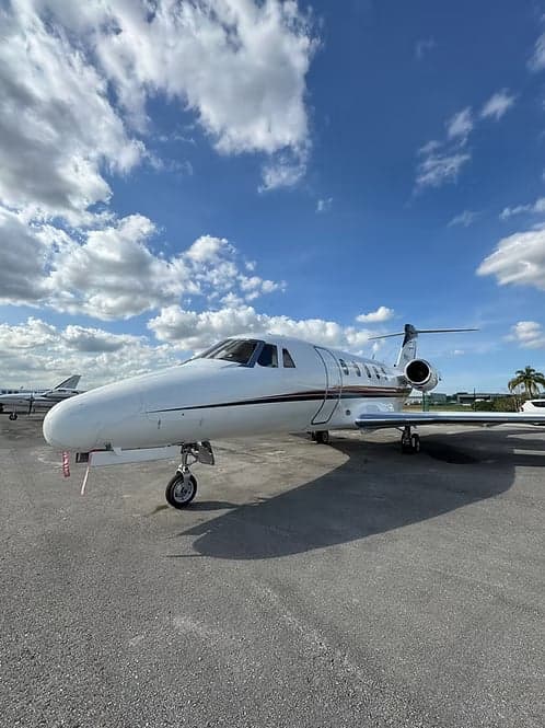 Cessna Citation CJ3+ on the tarmac with a blue sky and clouds.