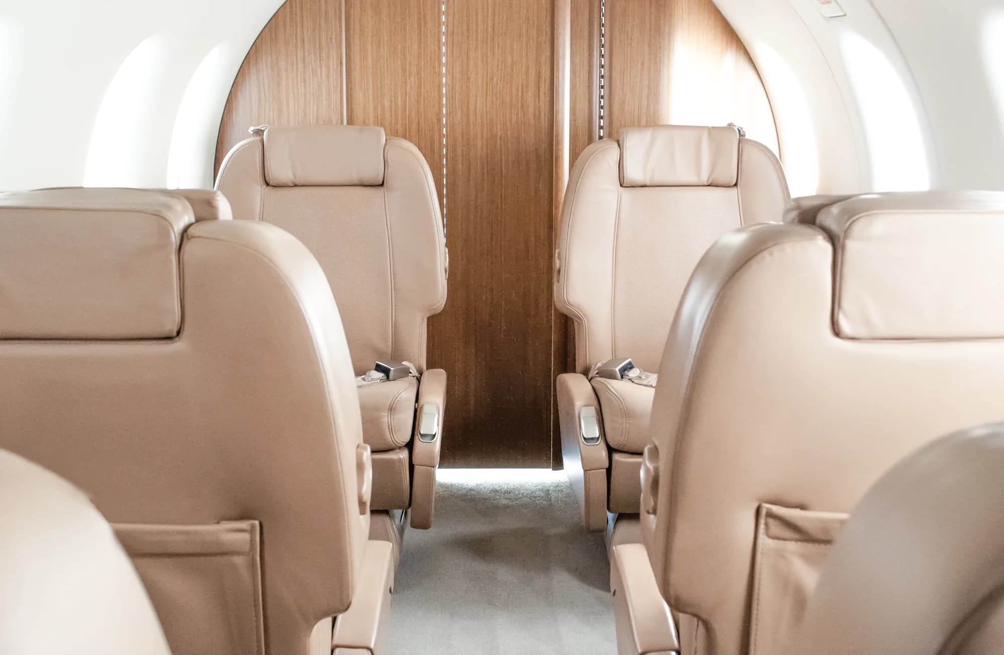 Close-up view of tan leather passenger seats in the cabin of a Pilatus PC-12 aircraft.