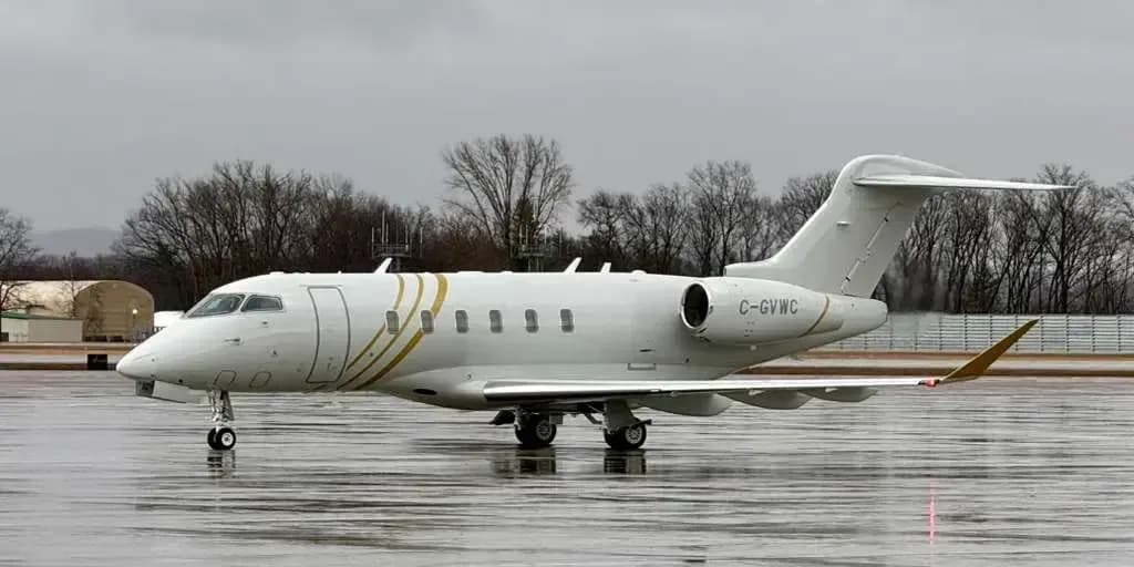 Side view of a Challenger aircraft with a white and gold paint scheme on the tarmac.