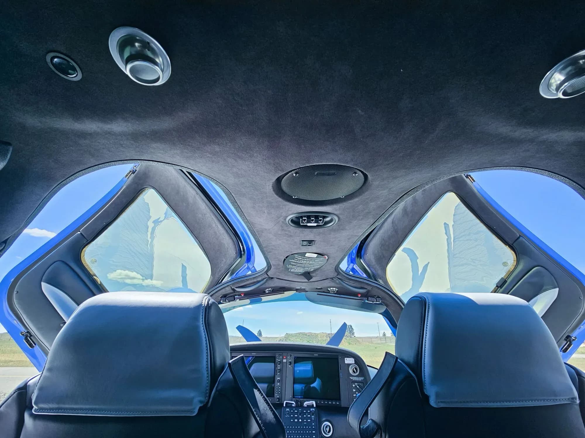 The interior of the Cirrus SR22T cabin looking forward, with the cockpit visible and the gull-wing doors open to the sky.