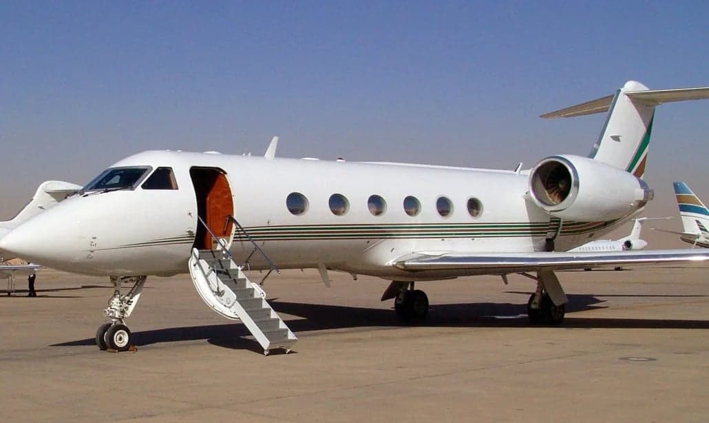 A white Gulfstream jet parked on the tarmac with the door open and stairs extended.
