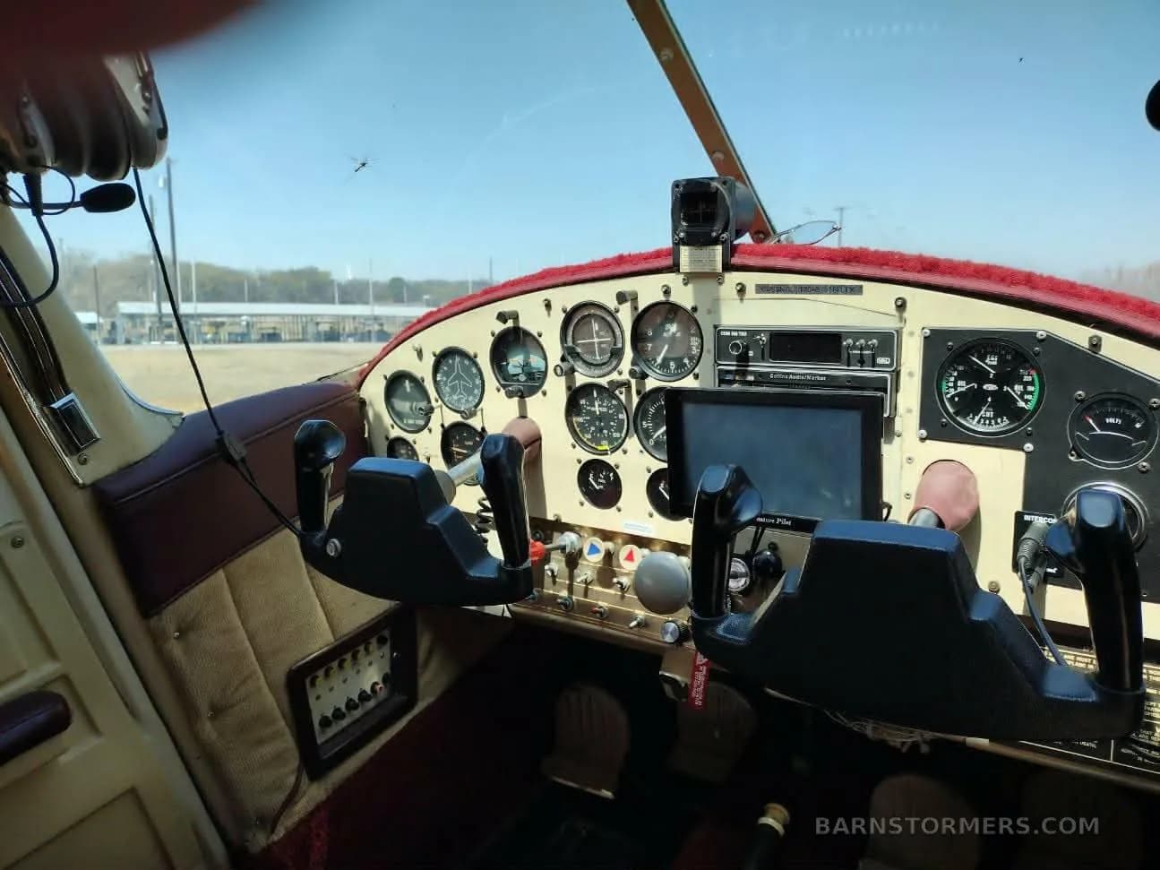 The cockpit of a small aircraft, featuring a classic instrument panel with analog gauges, a modern display, and dual yokes.