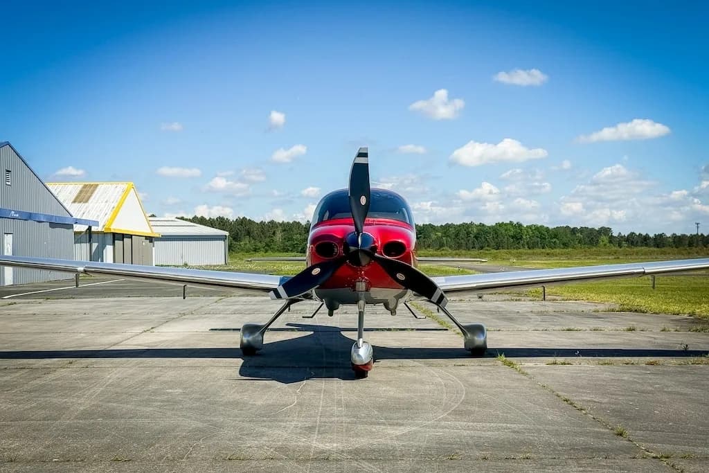 A head-on view of the red and silver Cirrus SR22 GTS aircraft parked on a tarmac.