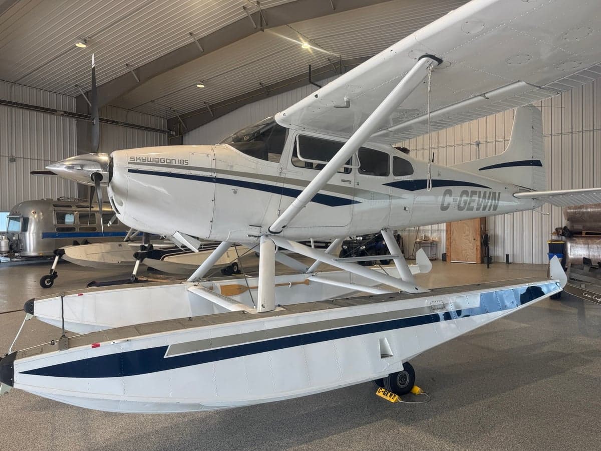 A Skywagon 185 floatplane is parked inside a hangar.