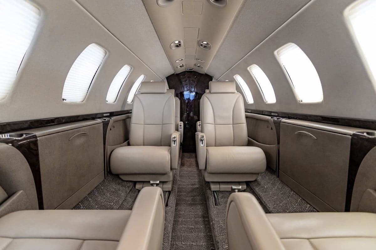 Aircraft cabin featuring leather seats and window shades.