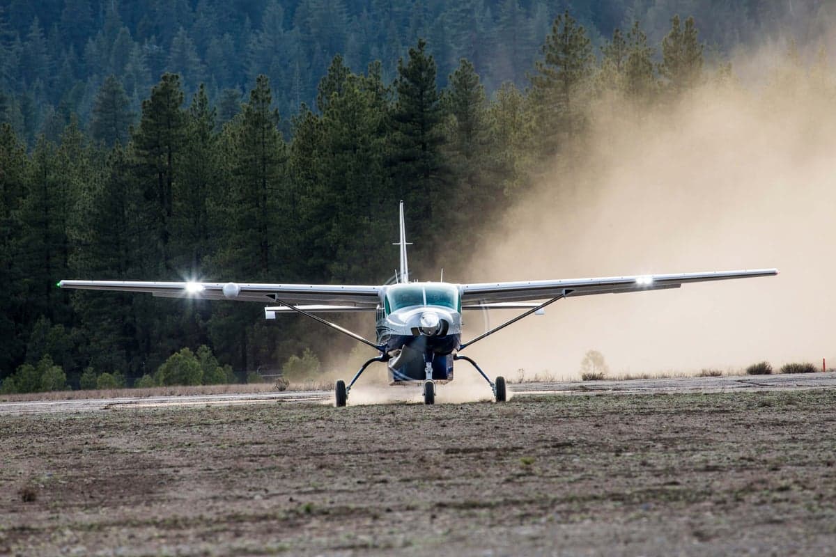 A Cessna Caravan kicking up dust on a dirt runway.