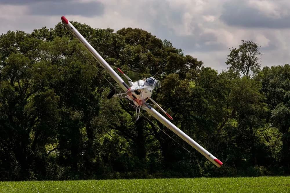 Crop duster aircraft flying low over a field.