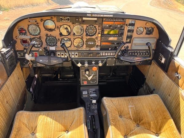 View of the aircraft's cockpit instrument panel and seats from the doorway.